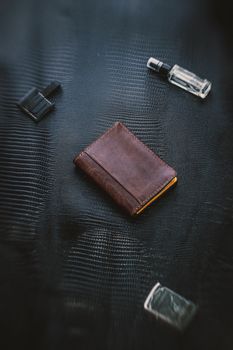 Top view of a stylish leather wallet with accessories on a textured surface.