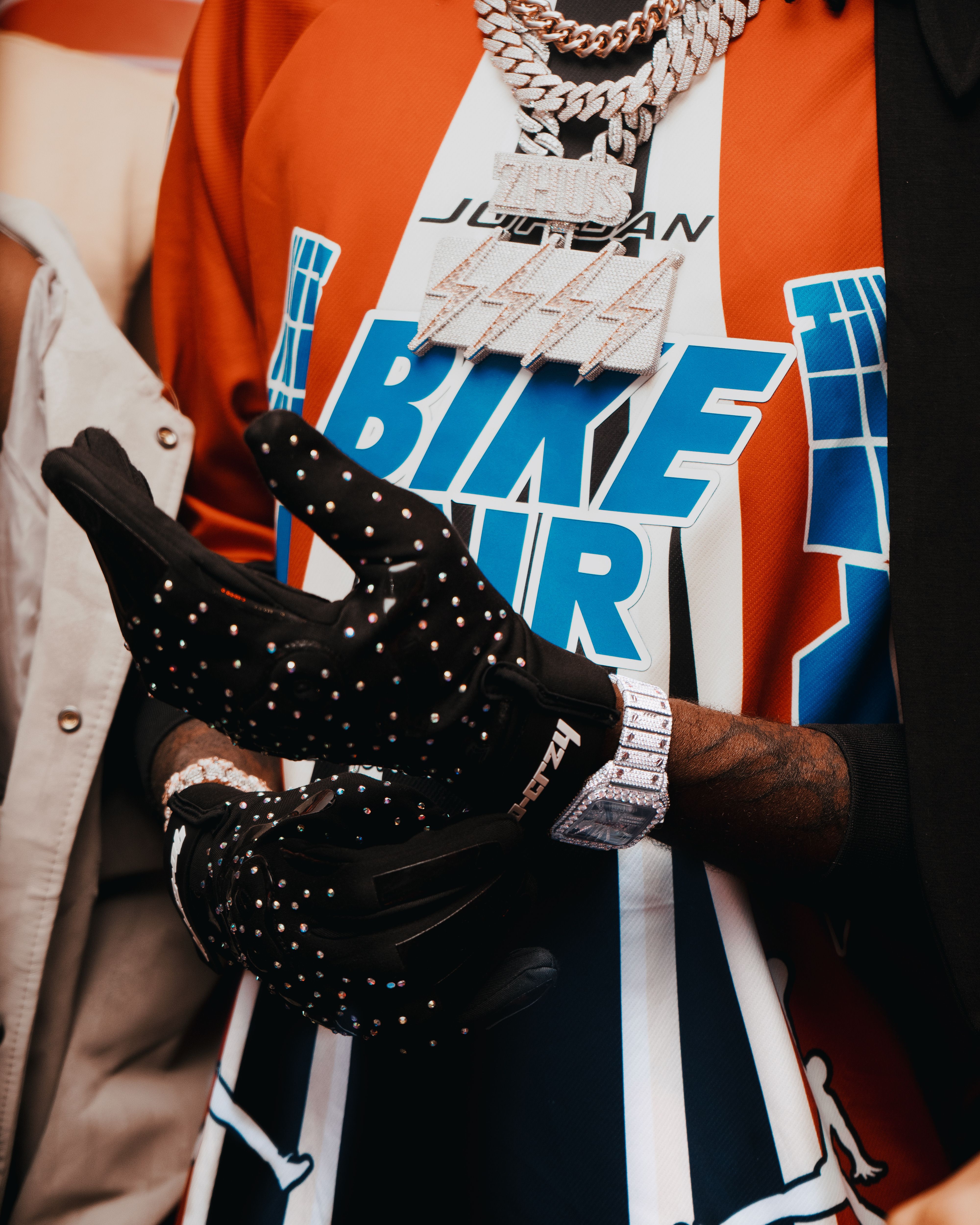 Stylish streetwear featuring bold lettering, gloves, and lavish jewelry.