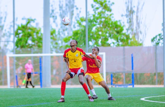Dynamic action shot of two male soccer players contesting for the ball on the field.