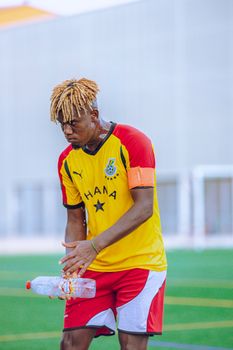 Young male football player in Ghana jersey practicing on outdoor field.