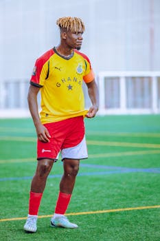 Male soccer player in Ghana team uniform on a football field.