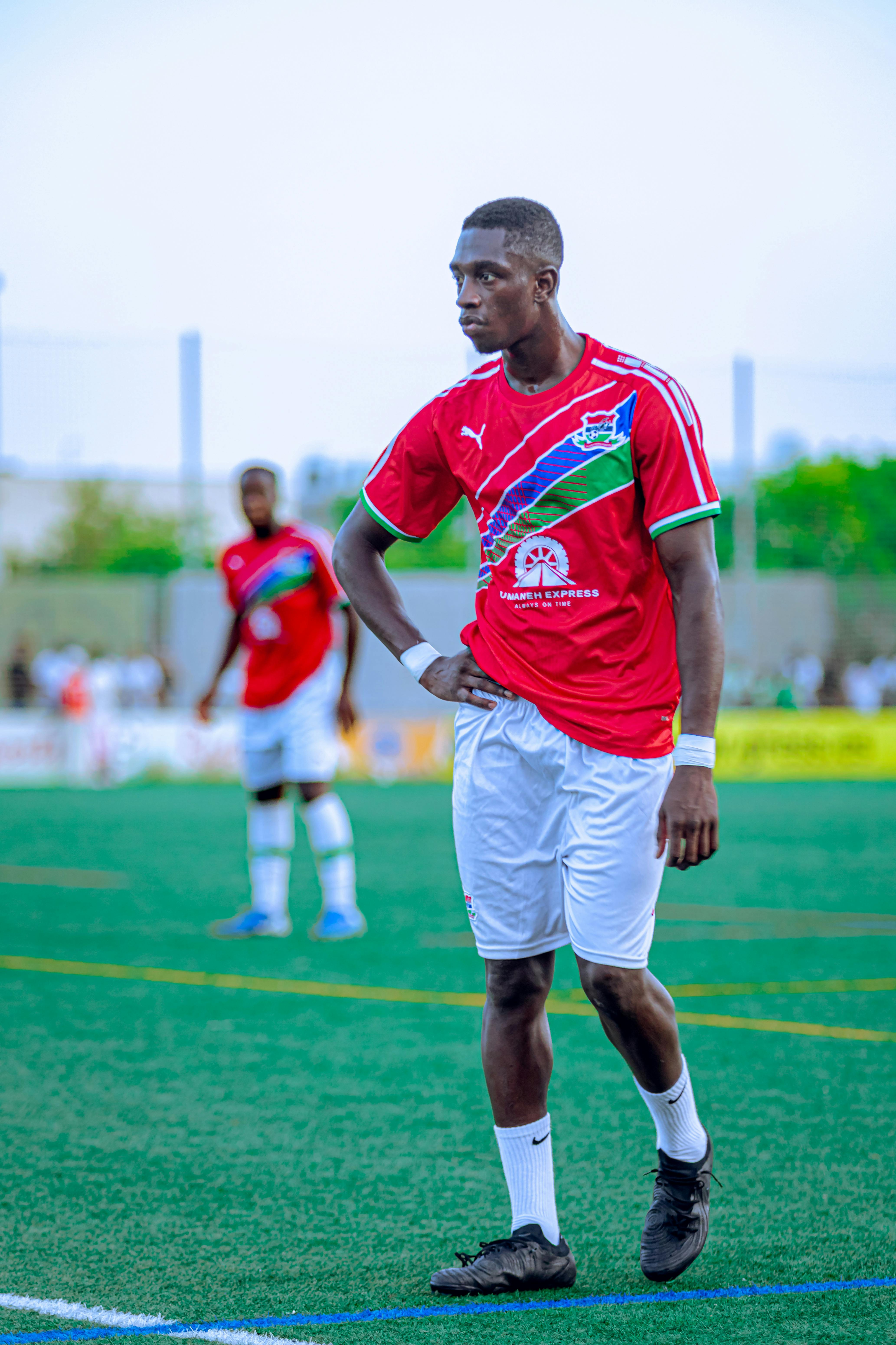 Focused soccer player in red jersey poised during a match.