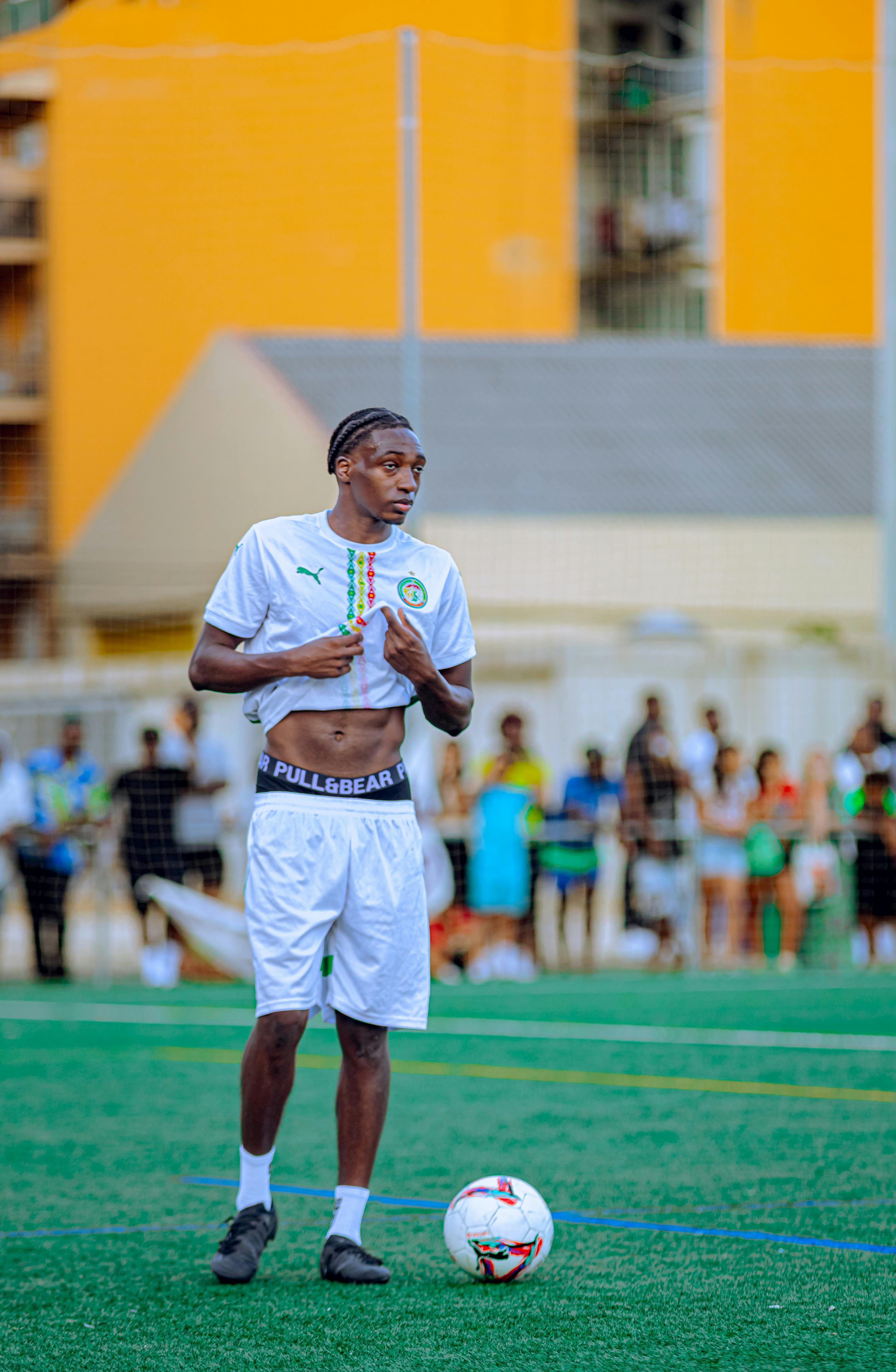 A young male soccer player stands on the field, adjusting his uniform before the game.