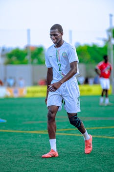 Soccer player in white uniform smiling on the field during a match.