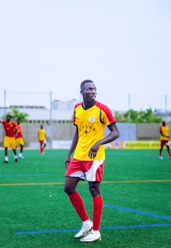 Ghanaian soccer player in action on a lush green field during a daytime match.