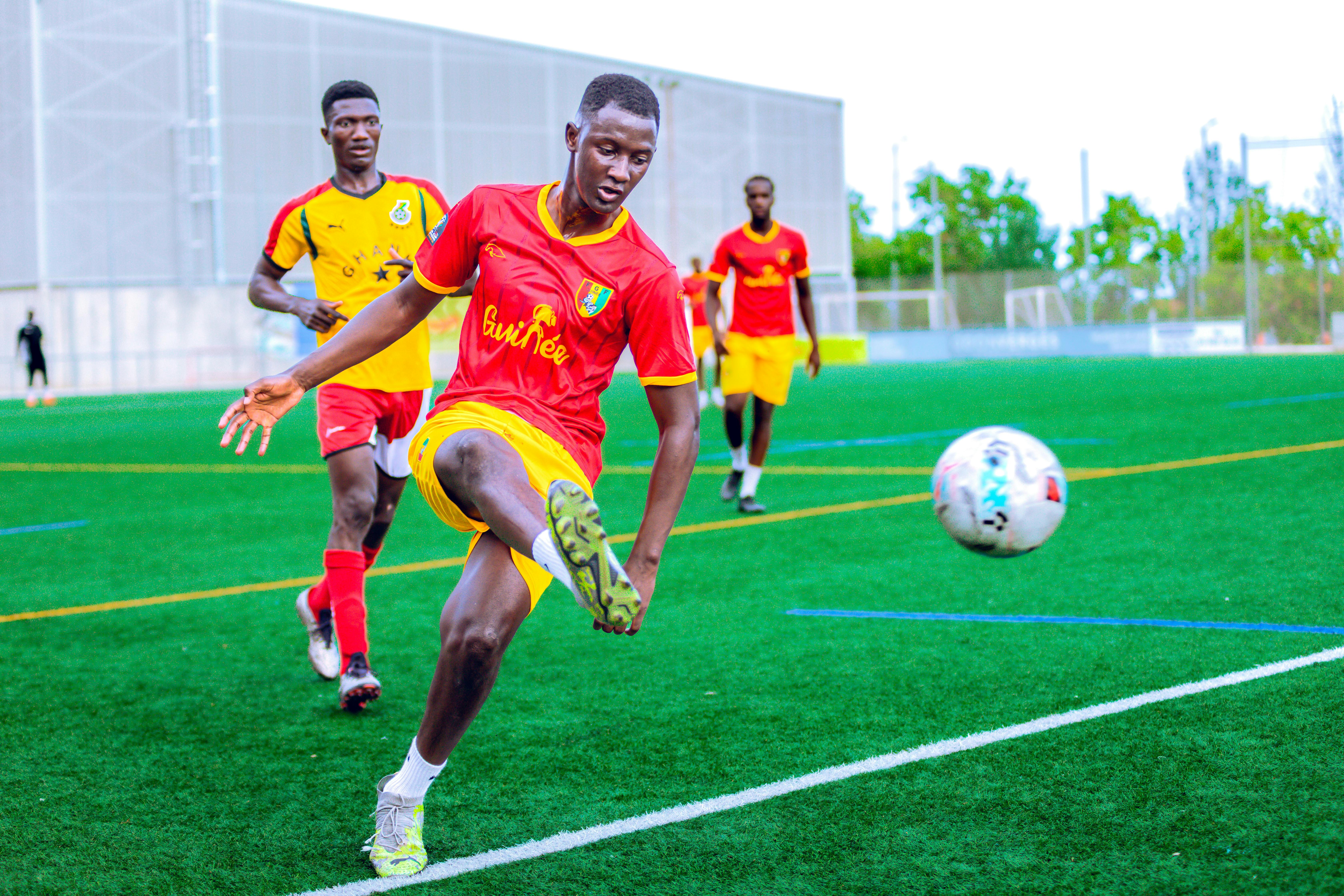 Action-packed soccer match with players in vibrant uniforms on a green field.