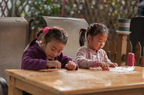 Free Two young girls engaged in a creative art project outdoors, emphasizing concentration and creativity. Stock Photo