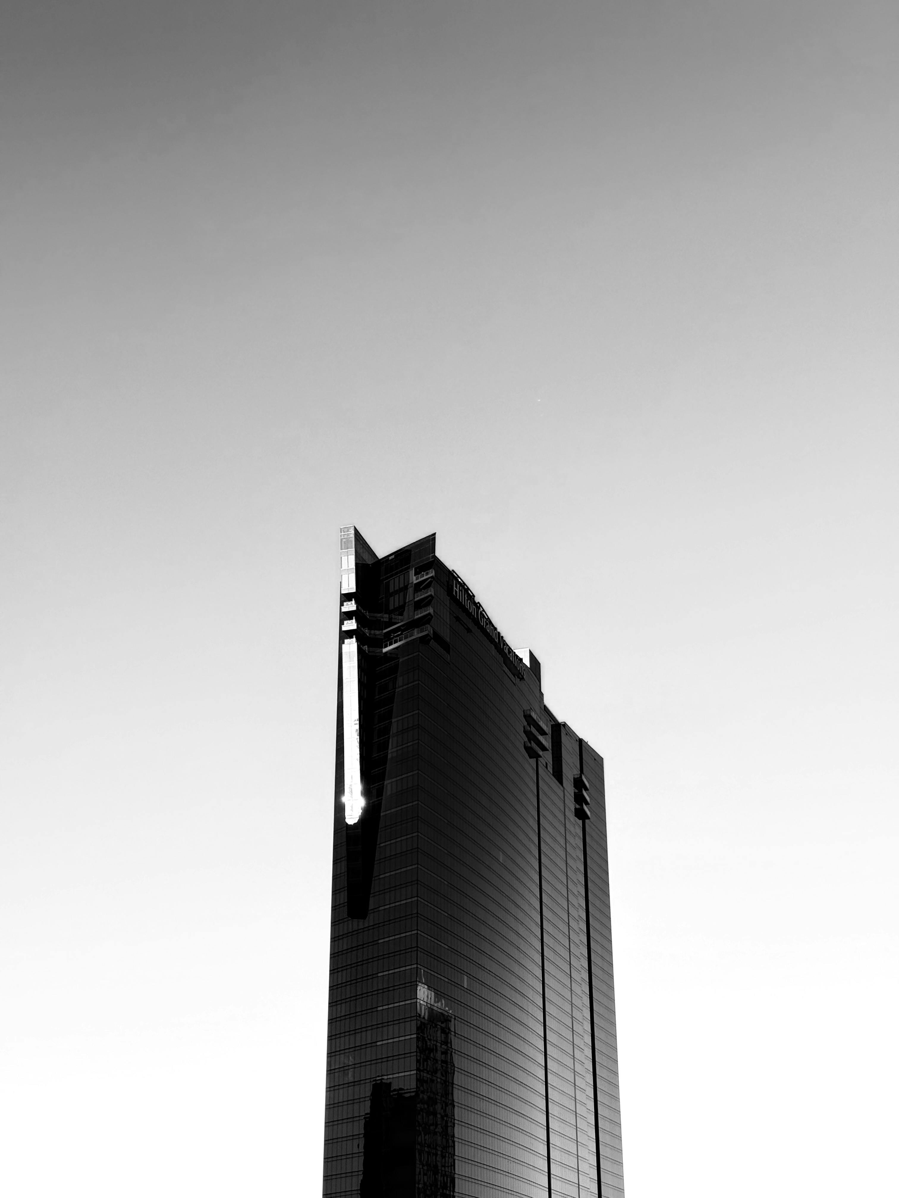 Gratuit Image minimaliste en noir et blanc d'un gratte-ciel moderne contre un ciel clair. Photos
