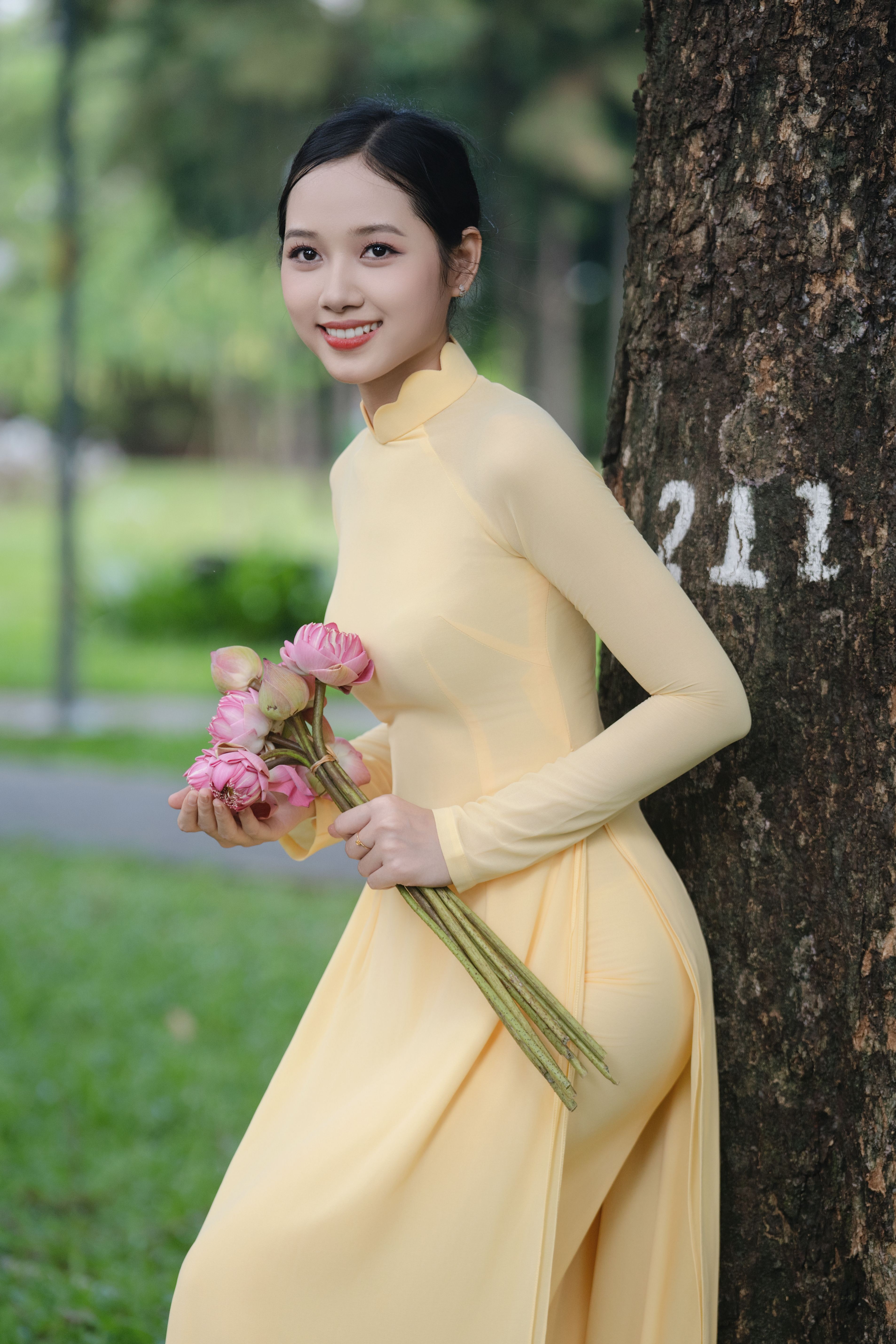 Young Woman in Yellow Dress Holding Pink Lotus Flowers · Free Stock Photo