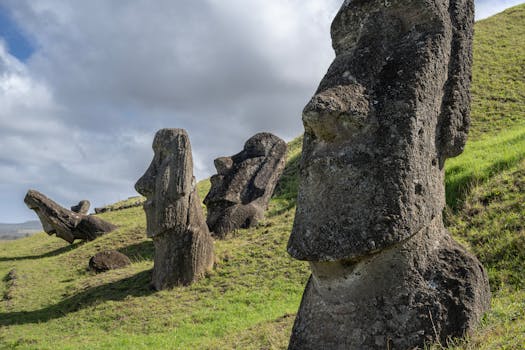 Moai statues on Easter Island, Chile, standing on a grassy hillside under a partly cloudy sky.