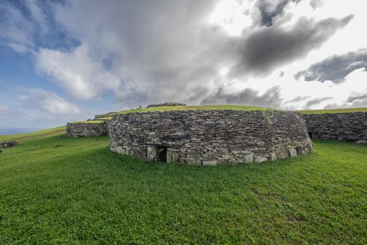 Exploring historical stone architecture on a grassy hill in Valparaíso, Chile under dramatic skies.