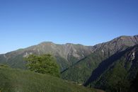 Clear blue sky over lush green mountains provides a serene natural setting.
