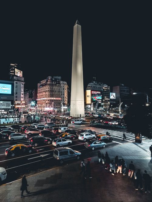 Free Vibrant street scene at night in Buenos Aires featuring the iconic Obelisk, bustling traffic, and city lights. Stock Photo