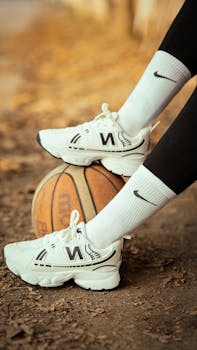White sneakers resting on a basketball outdoors, fall setting.