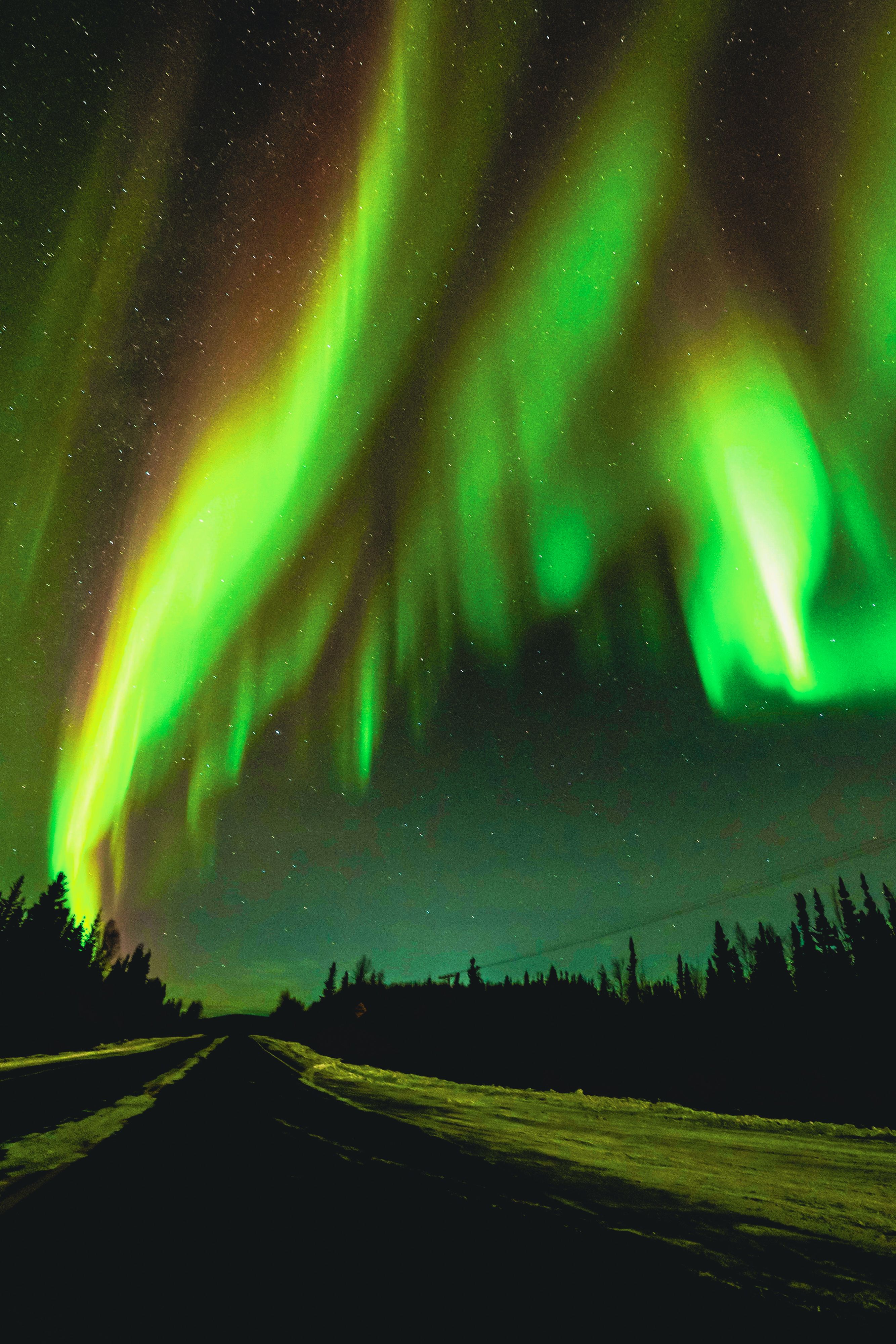 Stunning northern lights illuminating a winter night sky over a snowy road, peaceful and mesmerizing.