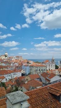 Explore the charming red-roofed architecture of Lisbon against a bright blue sky.