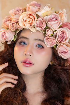Close-up portrait of a woman wearing a floral crown of pink roses, exuding elegance.