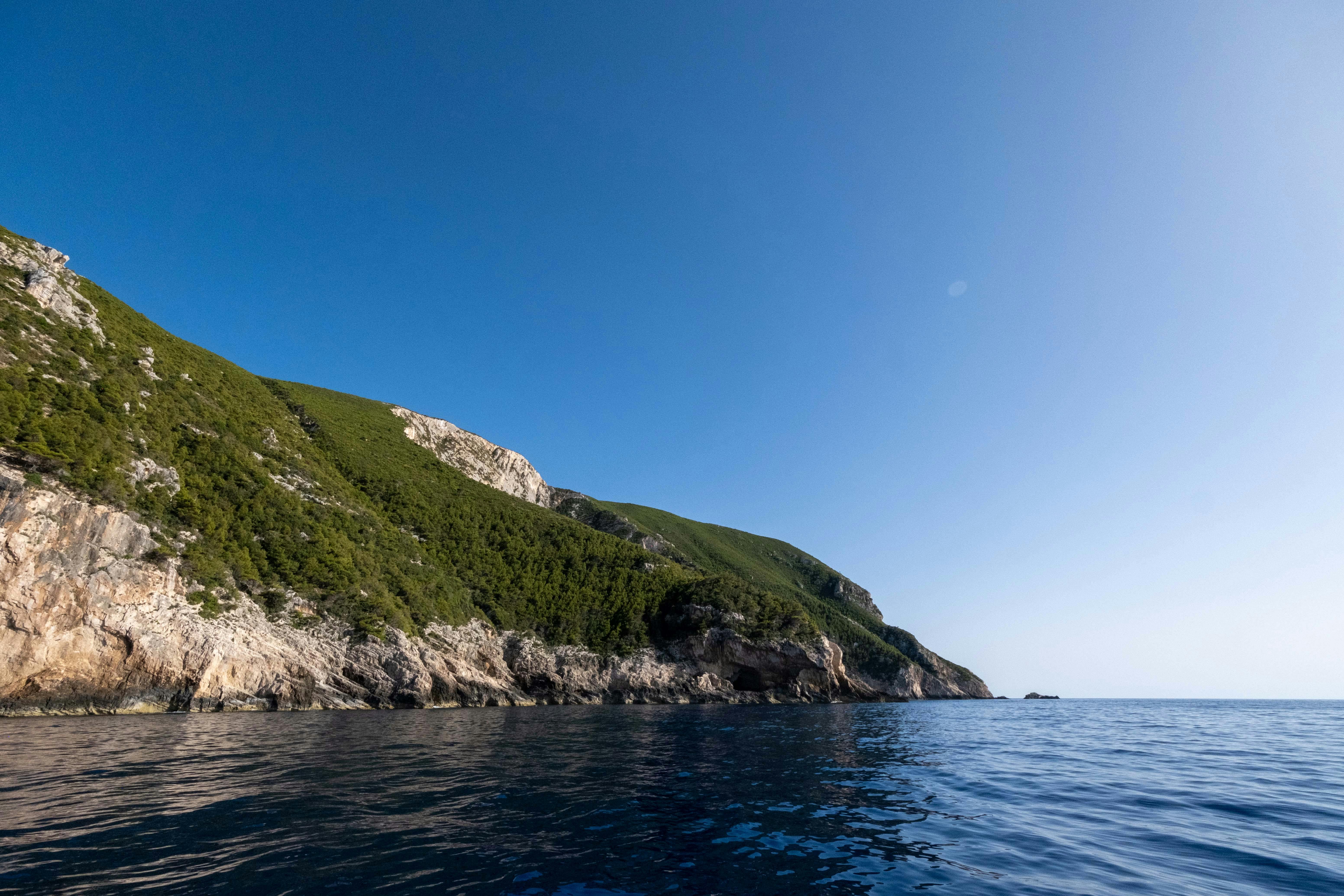 Breathtaking view of lush green cliffs meeting the azure sea under a clear blue sky.