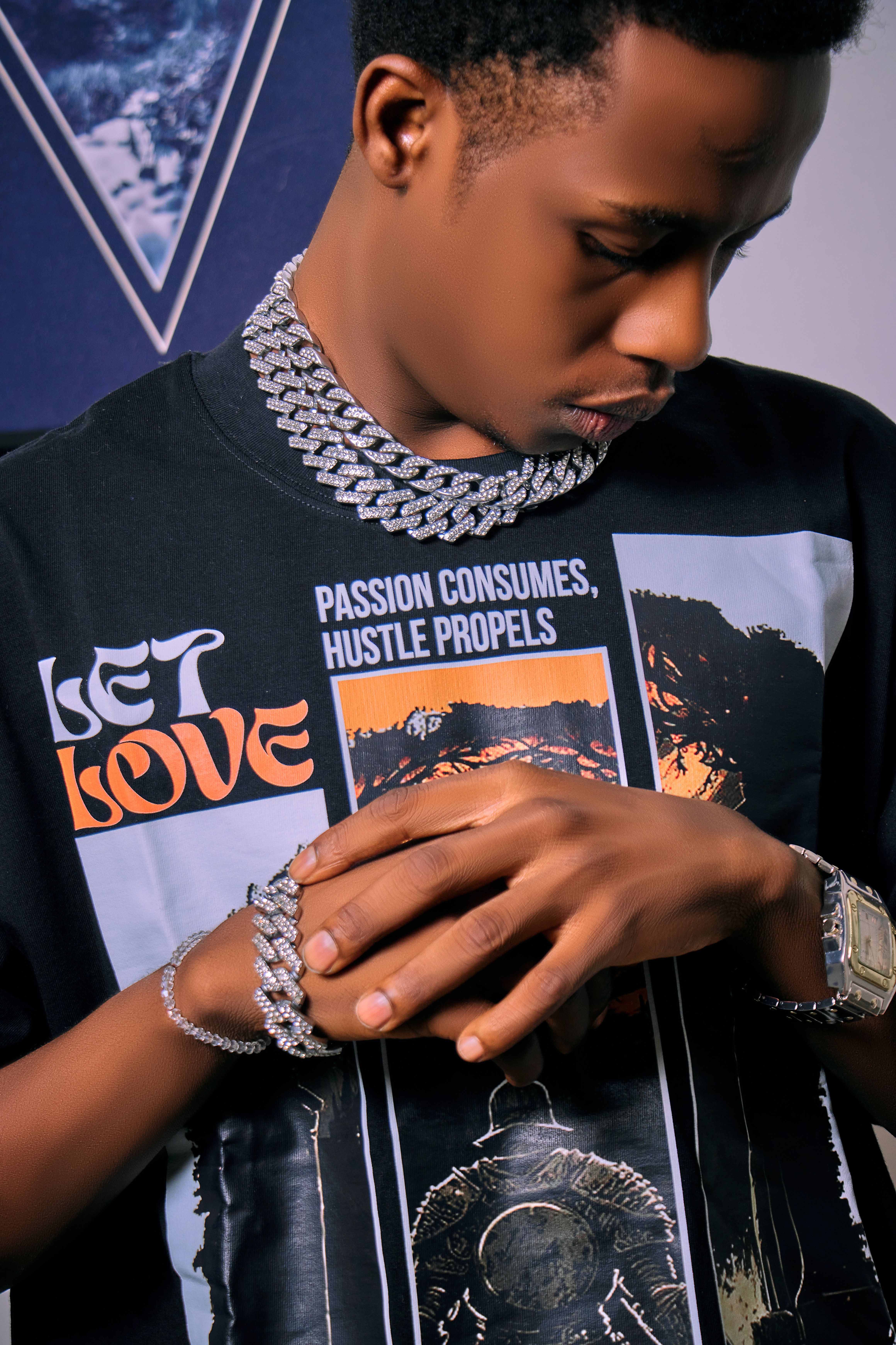 Young man wearing graphic tee and stylish chains, with focus on modern street fashion.