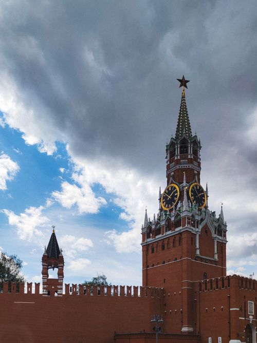 Free View of the iconic Spasskaya Tower at Moscow Kremlin in Russia beneath a dramatic cloudy sky. Stock Photo