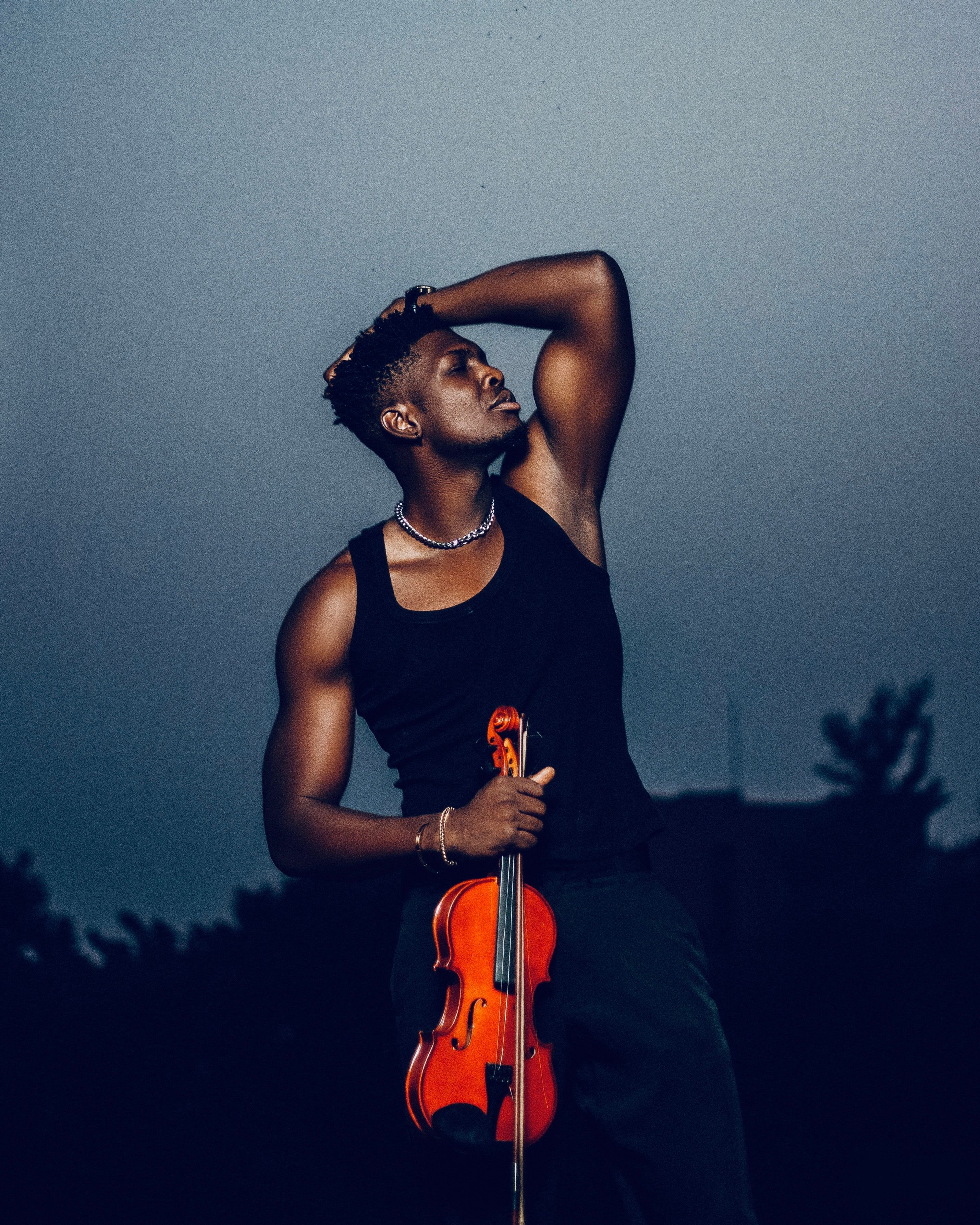 Artistic portrait of a young man holding a violin at twilight, evoking a dramatic and moody atmosphere.