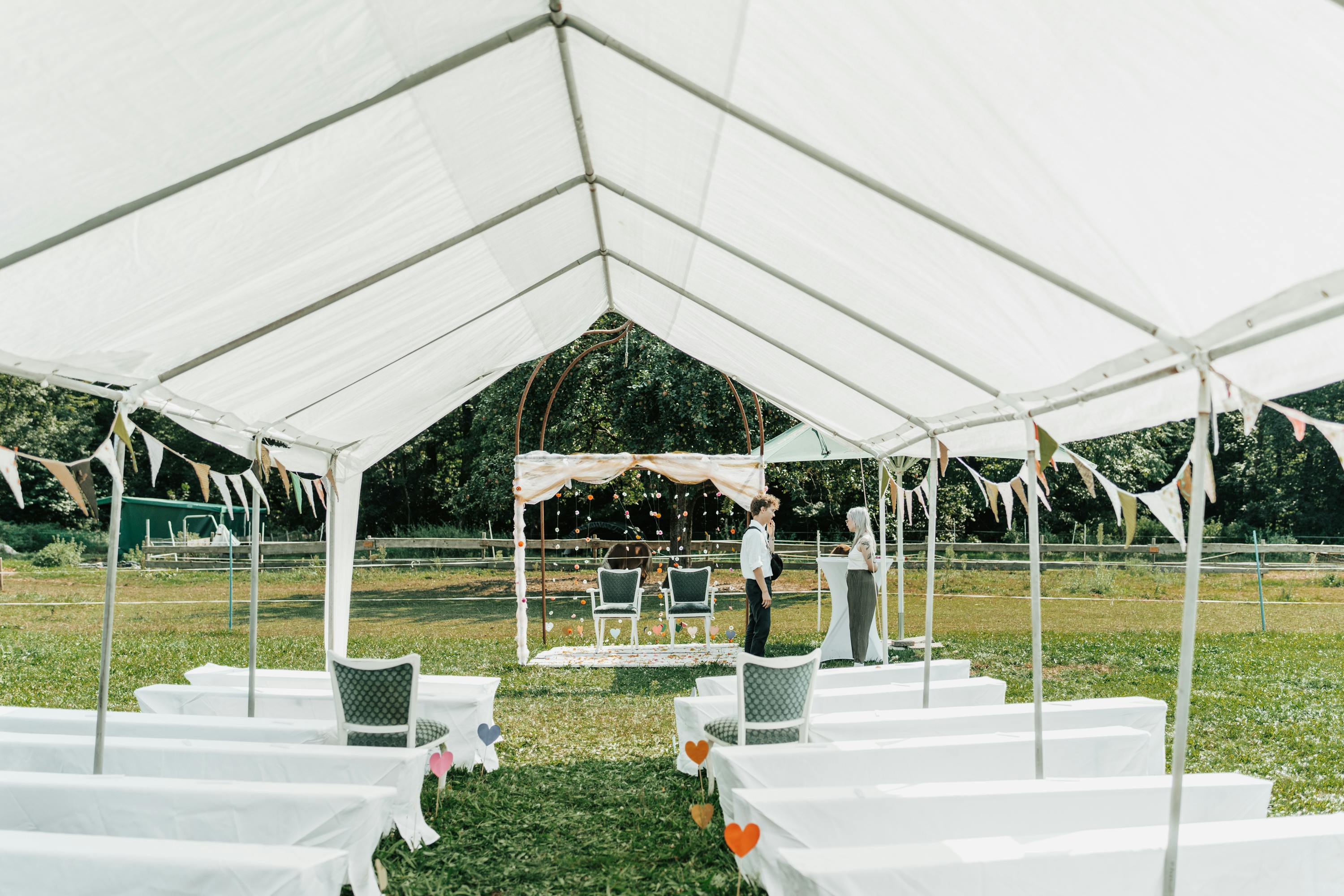Outdoor Wedding DJ Setup: Sound, Power & Weather Planning - A beautiful outdoor wedding setup under a white tent with chairs and decoration.