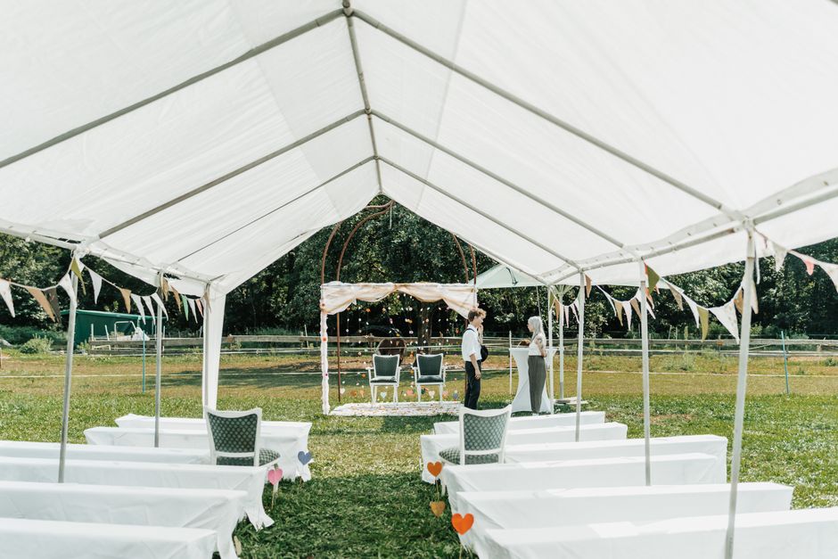 Outdoor wedding setup under a white tent with chairs and decorations in Denver