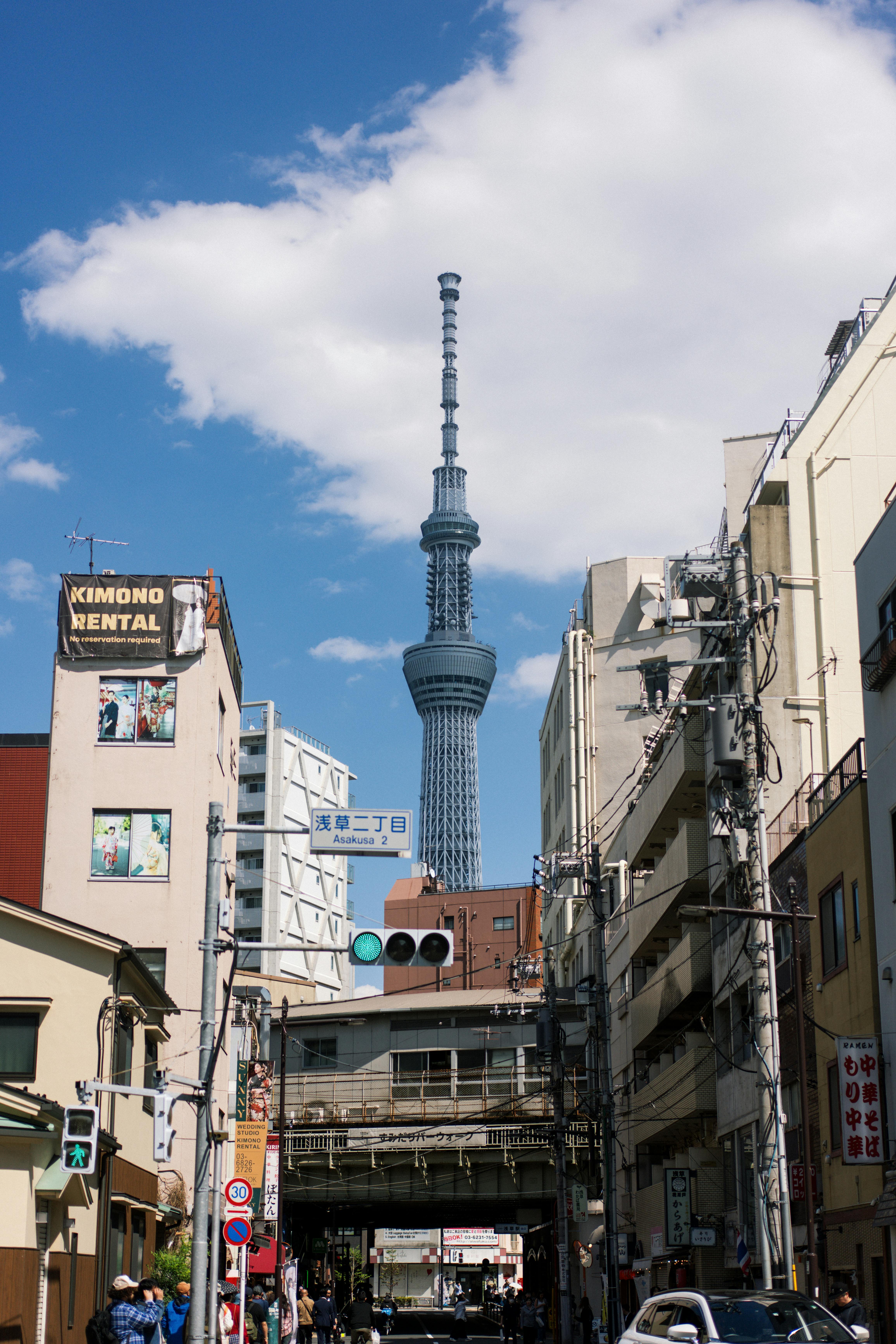 View of Tokyo Skytree amid bustling street and city buildings on a clear day.