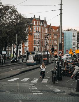 Street scene in Amsterdam with cyclist, tram, and iconic architecture highlighting urban life.