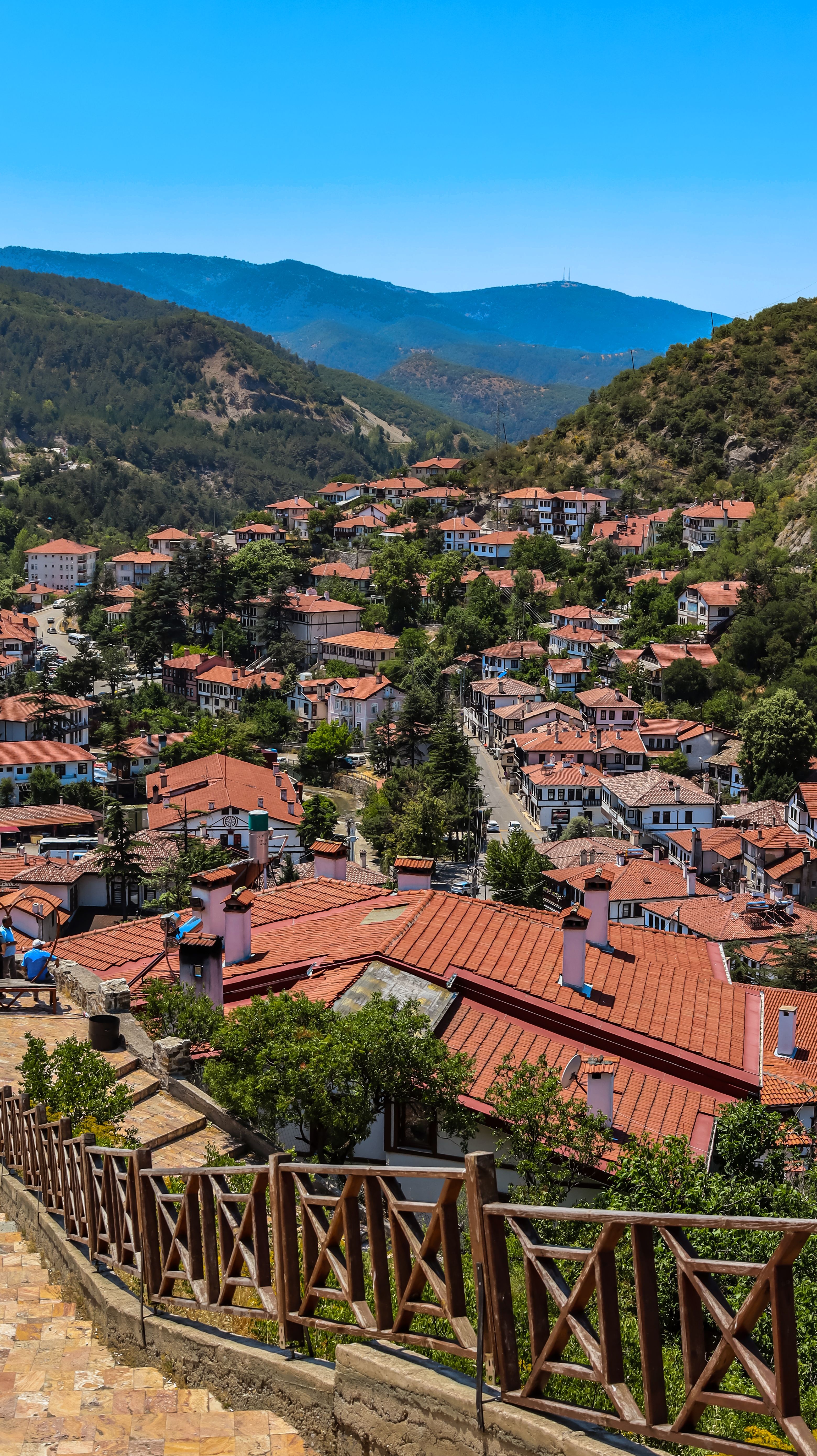 A picturesque view of Bolu, Türkiye showcasing red-roofed houses amidst lush greenery under a clear blue sky.