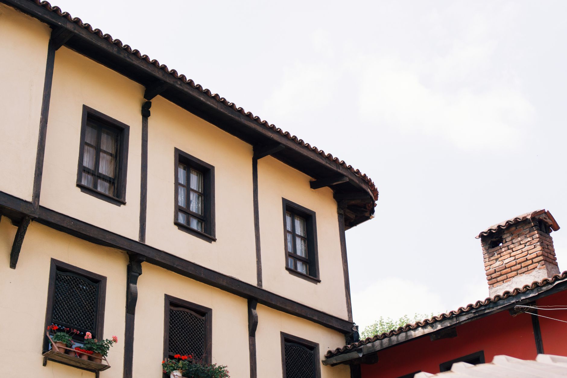 Charming rustic architecture featuring wooden beams and vibrant window flowers.
