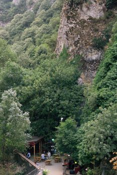 Charming outdoor cafe nestled in a lush green valley with natural rock formations.