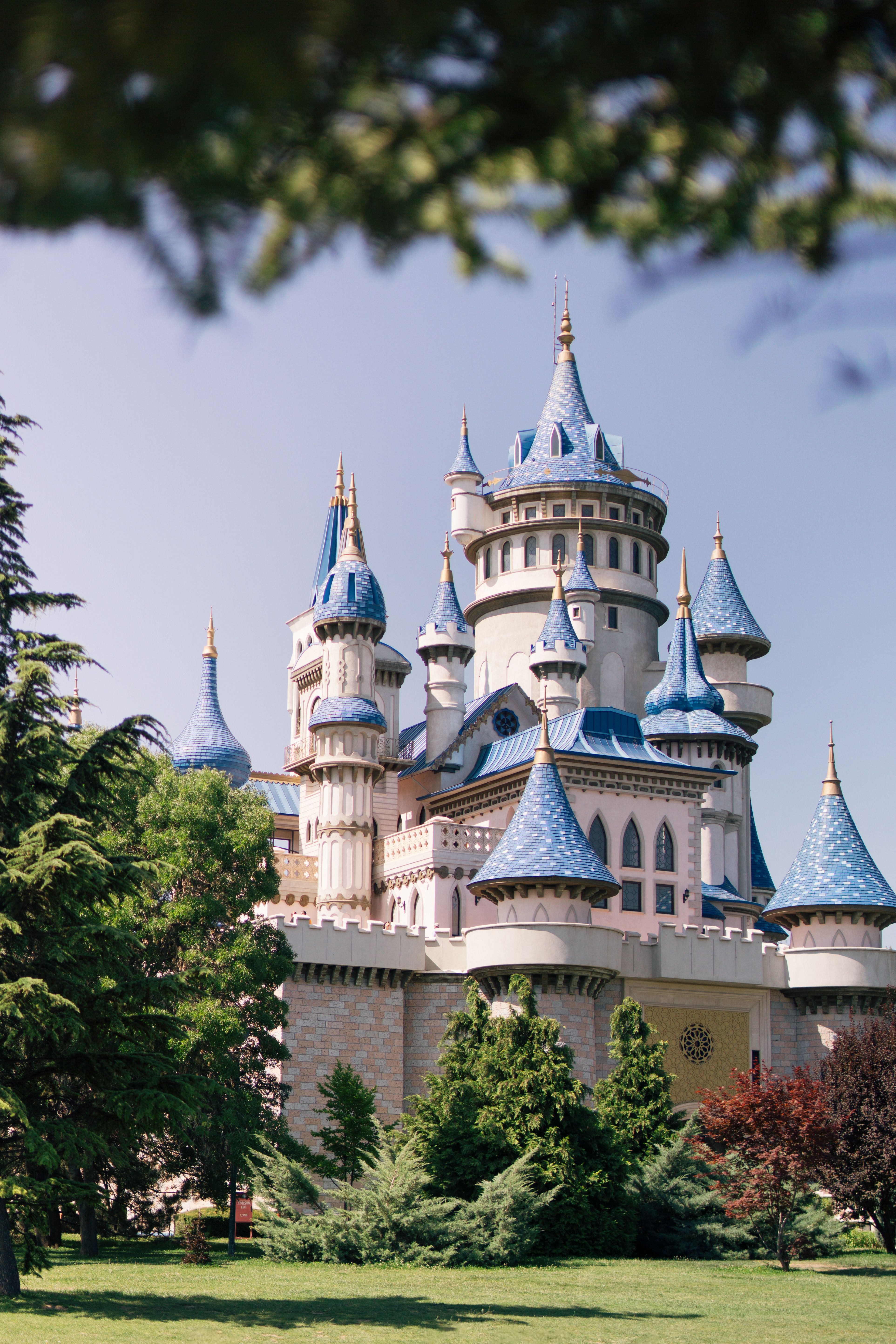 Beautiful fairytale castle with blue turrets in Eskişehir, Türkiye, surrounded by lush greenery.