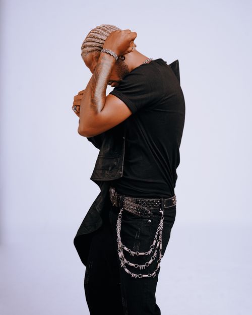 Free Man in trendy black outfit with chains, posing dynamically on a neutral background. Stock Photo