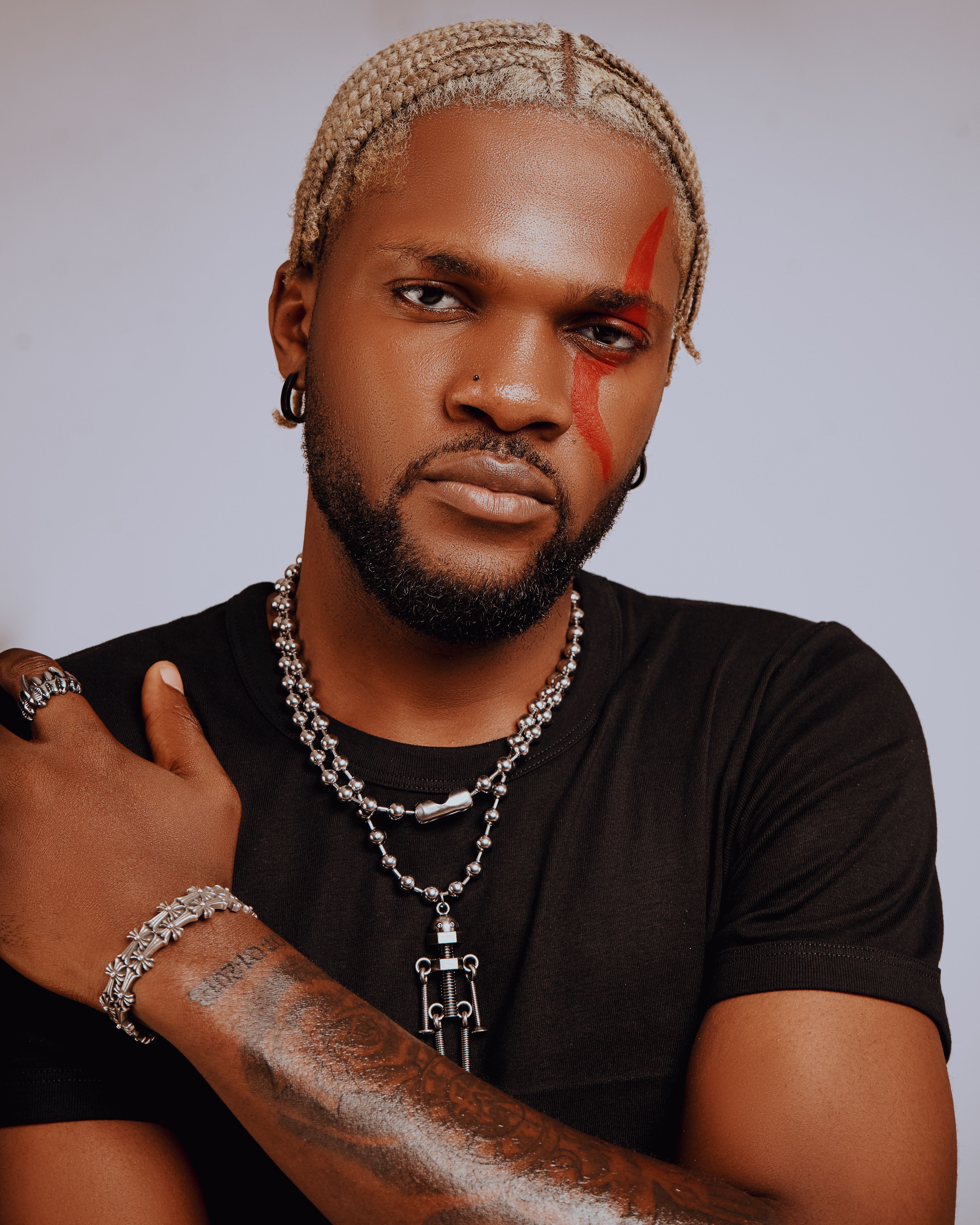 Stylish man with face paint, jewelry in an artistic portrait.