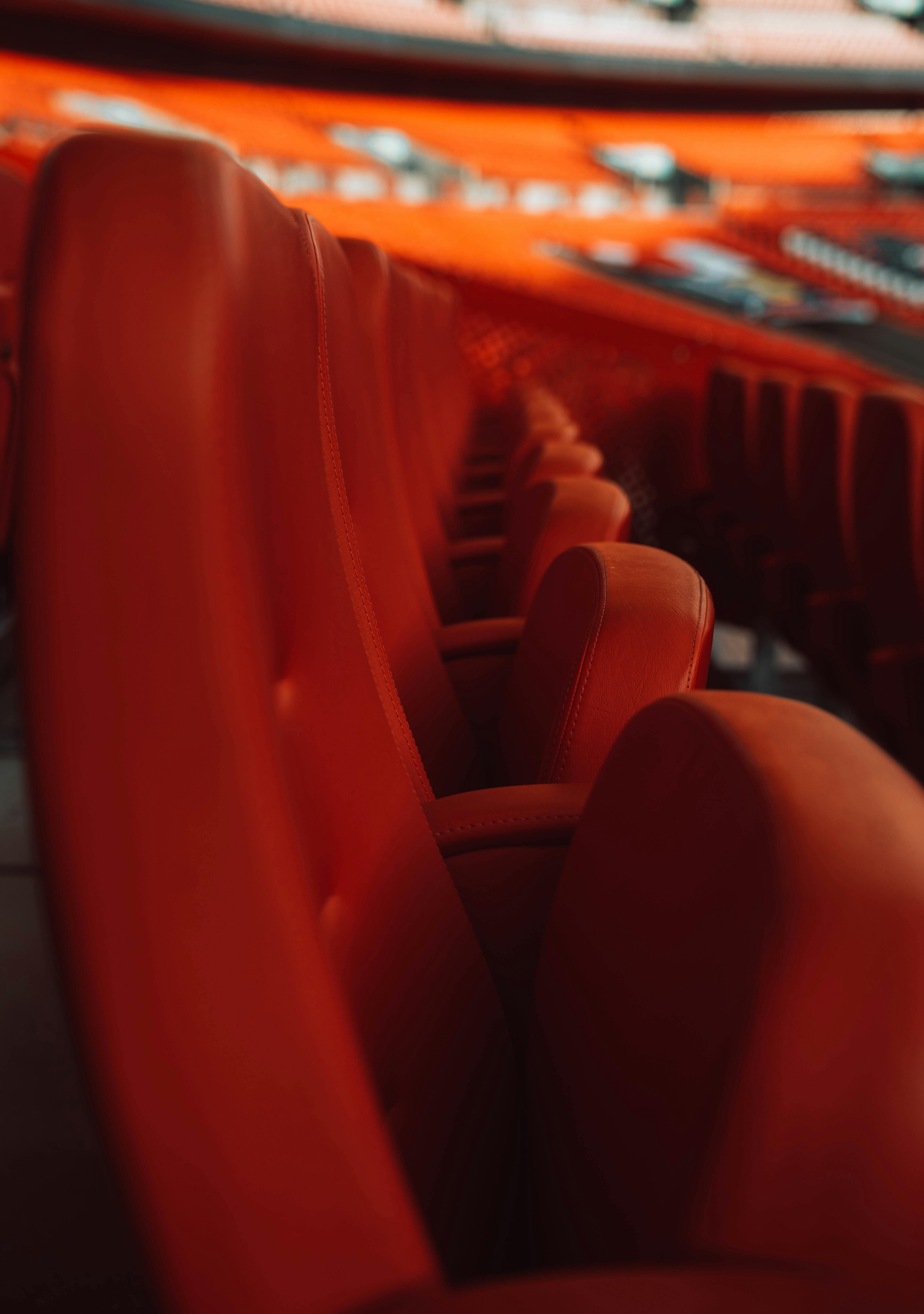 Free Close-up of vibrant red theater seats in an empty auditorium with a warm atmosphere. Stock Photo