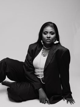 Black and white portrait of a woman in an elegant pose wearing a suit and pearls.