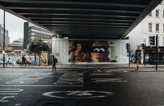Street art and graffiti embellish a cityscape under an urban bridge, capturing modern artistic expression.