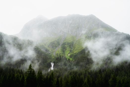 Scenic view of a mist-covered mountain and waterfall