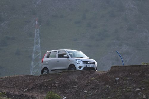 Free A white SUV parked on a rugged mountain road with power lines in the background. Stock Photo