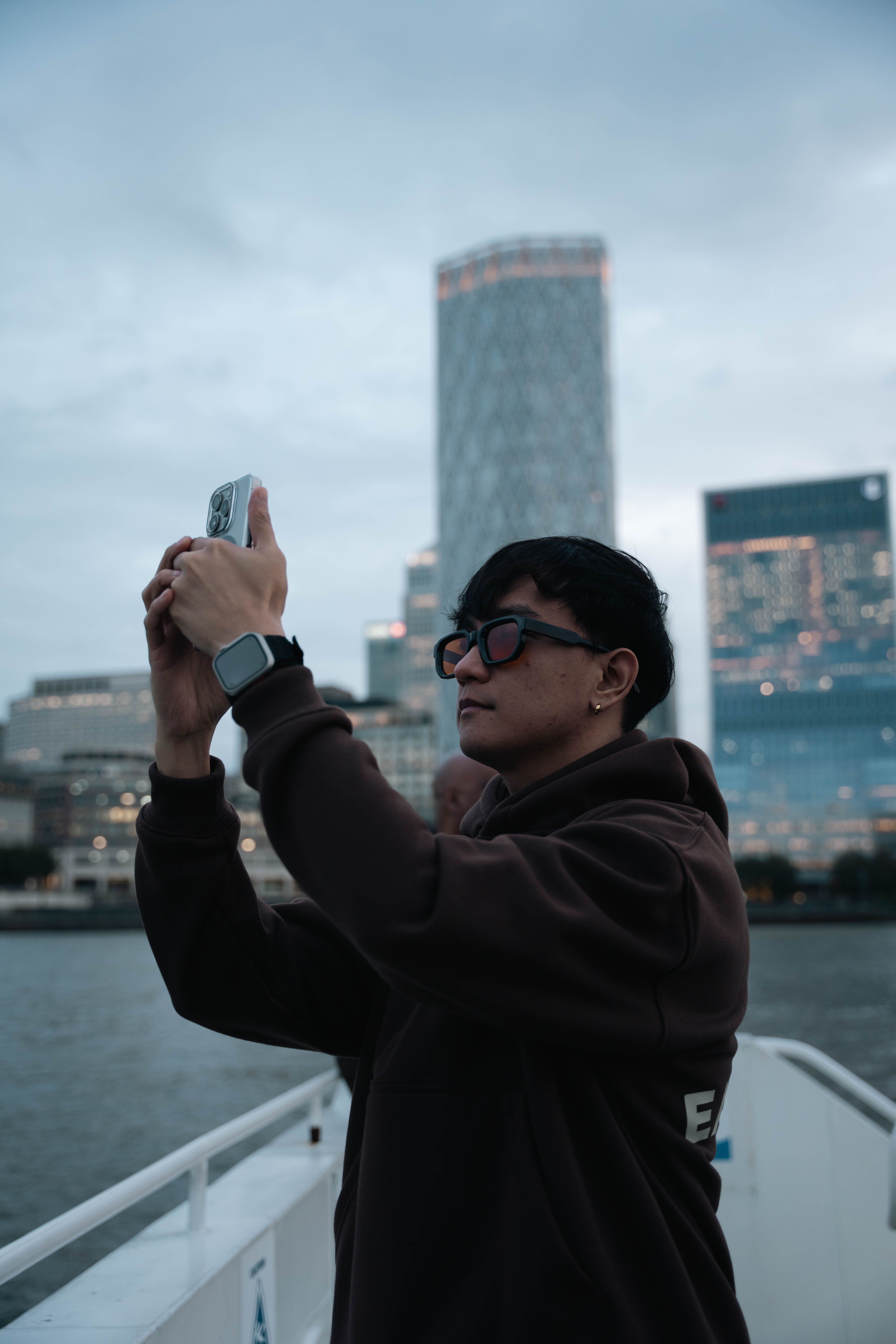Person capturing cityscape on a bridge during twilight in a modern city.