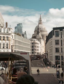 View of St. Paul's Cathedral from a bustling London street with people and double-decker bus.