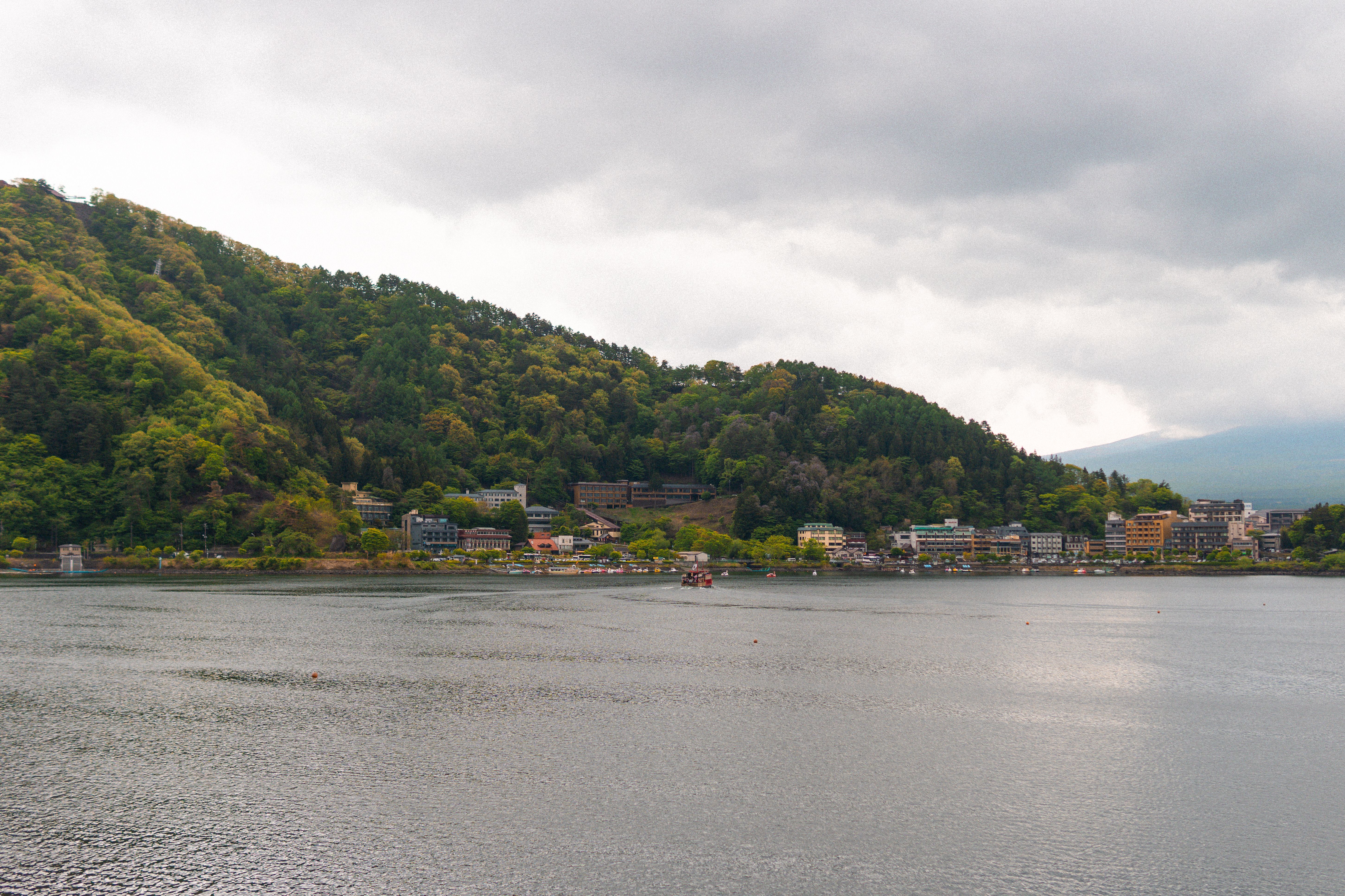 Peaceful landscape of Lake Kawaguchi with lush hills and cloudy sky, ideal for travel inspiration.