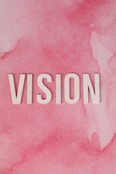 Inspiring 'VISION' text on a pink watercolor backdrop for motivation.