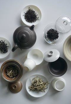 Elegant flat lay composition of a ceramic teapot and assorted loose tea leaves.