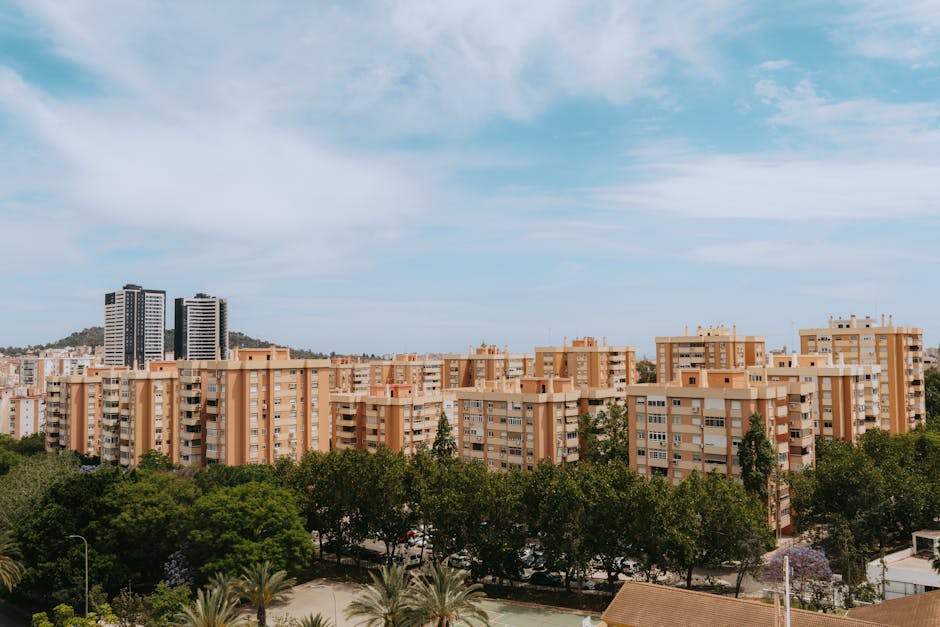 Aerial view of Málaga's urban skyline with orange apartment buildings under a clear blue sky.