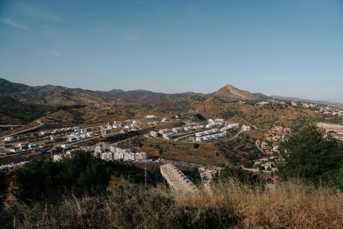 Free Capture of Málaga, Spain's scenic landscape featuring white buildings nestled in rolling hills under a clear summer sky. Stock Photo