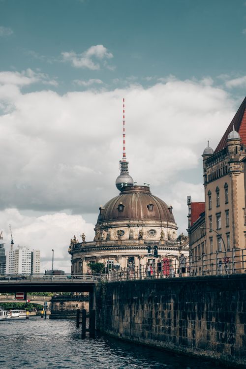 Free A picturesque view of Berlin's Bode Museum with the TV Tower in the background under a cloudy sky. Stock Photo