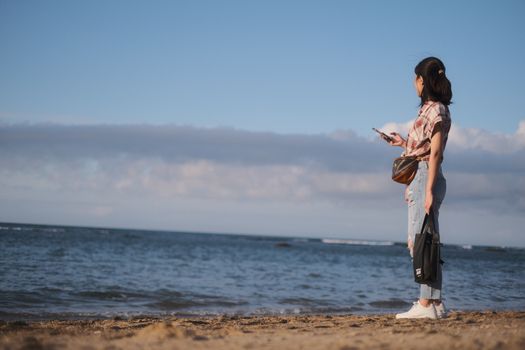 Casual young woman on a beach day, enjoying the view and using her phone.