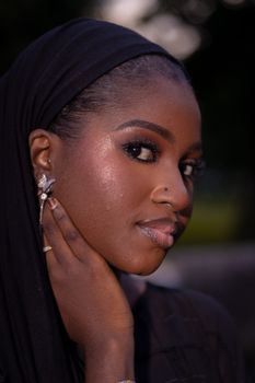 Close-up portrait of a woman in a hijab with elegant makeup and jewelry, showcasing grace and style.